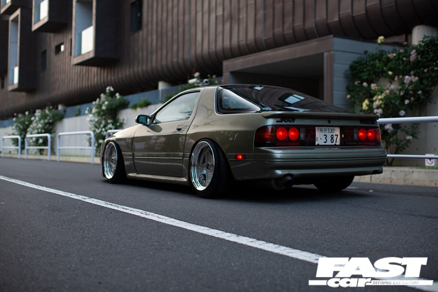 Rear left shot of a murky green tuned Mazda RX 7 FC Japana