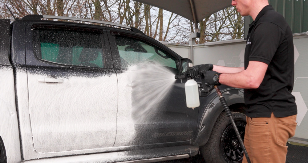 Man applying snow foam to a pick-up truck