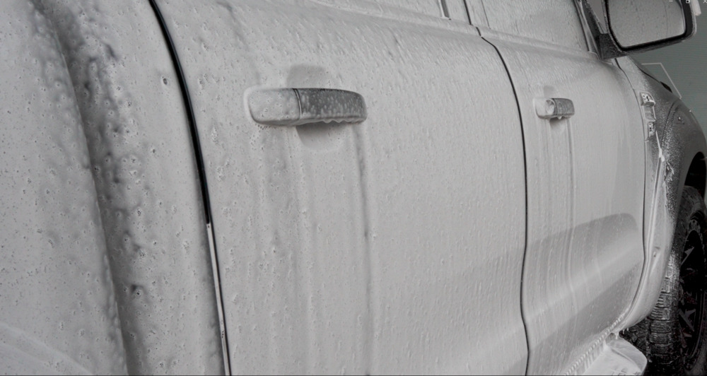 close up of snow foam running off a car it has been applied to